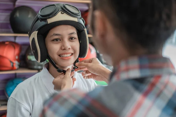 Frau trägt Helm mit Hilfe einer Verkäuferin beim Befestigen der Gurtschnalle — Stockfoto