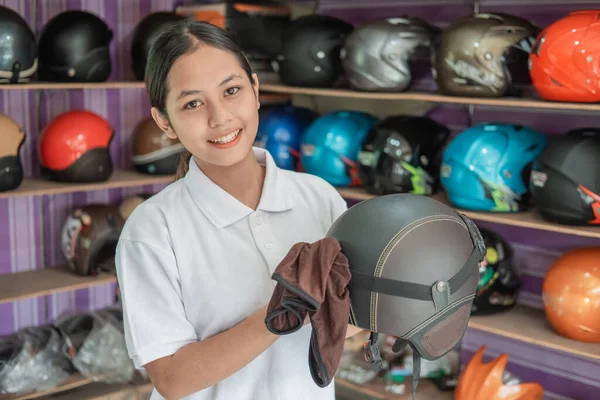 Mujer sonriente asistente de tienda casco de limpieza con tela —  Fotos de Stock