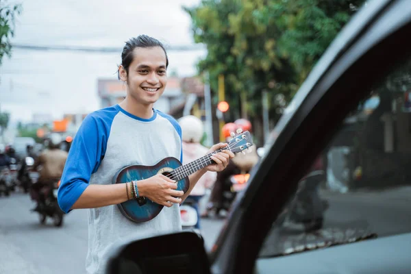 Sokak müzisyeni müzik aletleri kullanır ve trafik ışıklarının kesiştiği yerde arabanın önünde şarkı söyler. — Stok fotoğraf