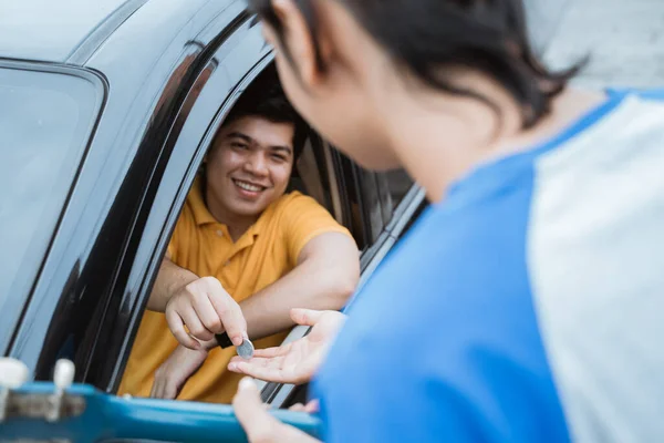 O homem sorrindo de dentro do carro dando moeda à mão da janela do carro para buskers — Fotografia de Stock