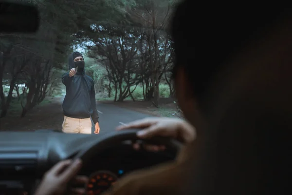 Mendigo usa uma faca para ameaçar parar um carro em uma estrada florestal — Fotografia de Stock