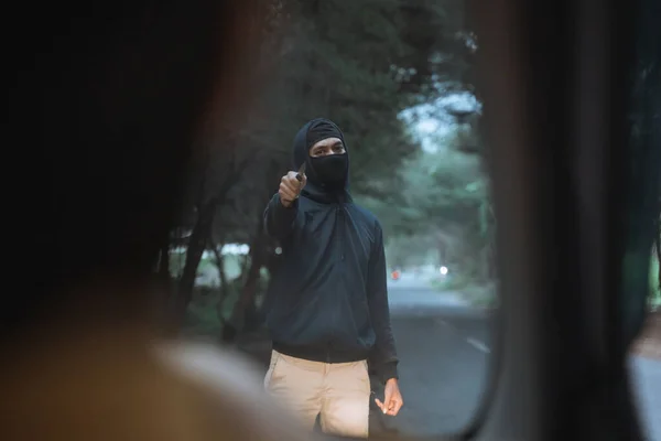 Hombre con una máscara utiliza un cuchillo para amenazar al conductor del coche — Foto de Stock