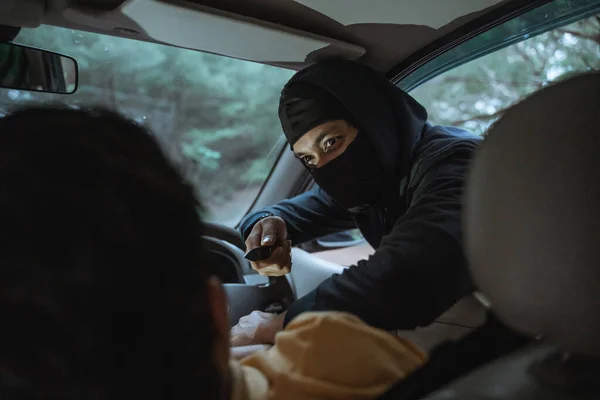 De man die de auto bestuurt wordt bang als een overvaller een mes op zijn nek richt vanuit het autoraam. — Stockfoto