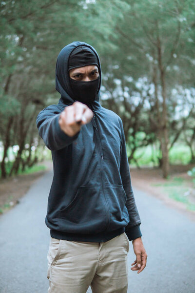 villain in a mask with a knife wearing black hoodie pointed the knife at the camera