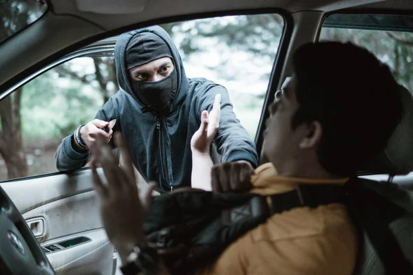 El bandido roba el auto de los hombres. Él la está amenazando entonces el hombre está sorprendido —  Fotos de Stock