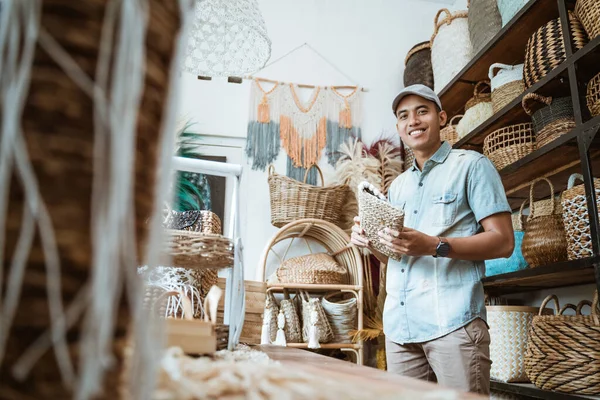 Jungunternehmer lächelt, während er ein Weidenportemonnaie in der Hand hält — Stockfoto