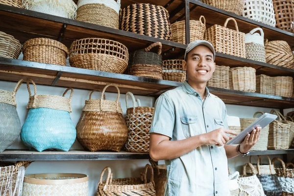 Glimlachende jonge ondernemer terwijl het houden van een digitale tablet met een handgemaakte zak op de achtergrond — Stockfoto