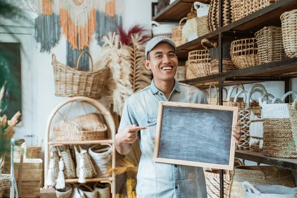 Jovem empreendedor segurando um quadro negro com o dedo apontando — Fotografia de Stock