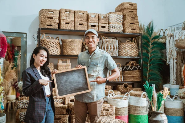 Azjatycki para przedsiębiorca trzymając tablicę z palcem wskazującym w sklep rzemieślniczy — Zdjęcie stockowe