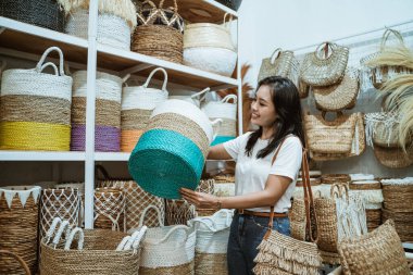 Bir kız sepet sepetini seçer ve büyütür. Hasır hasır sanatı arka planına karşı durur.