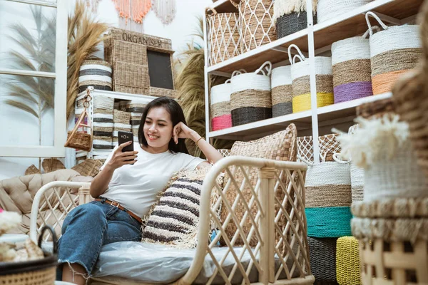 Vrouw terloops zitten op de bank met behulp van een smartphone — Stockfoto