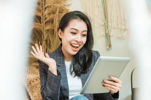 Uma mulher bonita feliz em um blazer usa um tablet digital — Fotografia de Stock