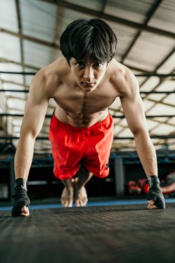 Bileğinde siyah kayış olan kaslı boksör ısınırken kendini yukarı kaldır.