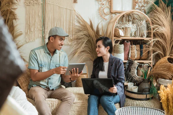 Designer man en vrouw ondernemer praten over de verkoop van handwerk met behulp van tablet en laptop computer — Stockfoto