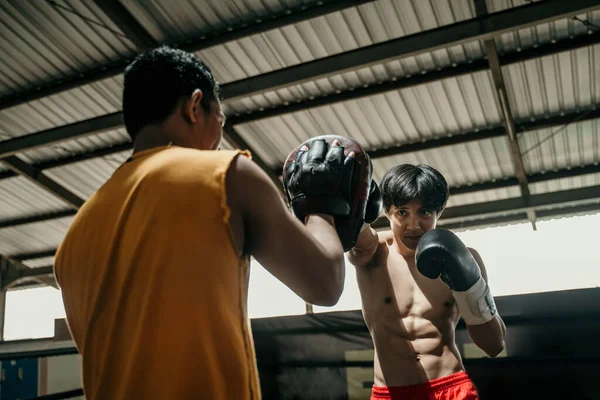 若い男のボクサーがトレーナーと競争するパンチ練習をする — ストック写真