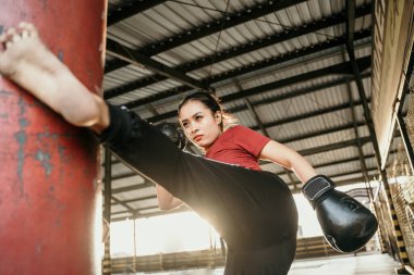 Genç kadın kum torbasına tekme atıyor.