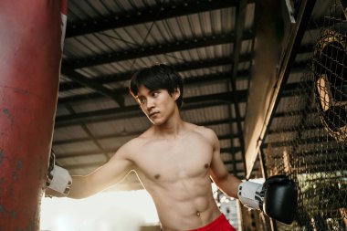 Ağır torbaya vuran Asyalı boksör.