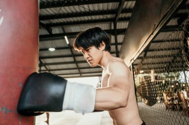 Asyalı boksör sınavı kum torbasına vuruyor.