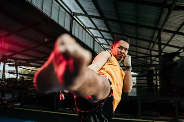 Close up de muay thai boxer em luvas de boxe fazer um pontapé do meio — Fotografia de Stock