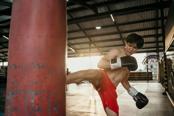 Den unge mannen tränar en spark på boxningssäcken — Stockfoto