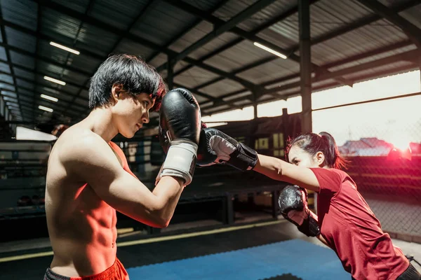 Combatiente femenino atacando con movimiento de puñetazo y boxeador masculino haciendo defender el movimiento — Foto de Stock