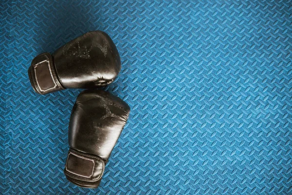 Black boxing gloves on blue iron flooring — Stock Photo, Image