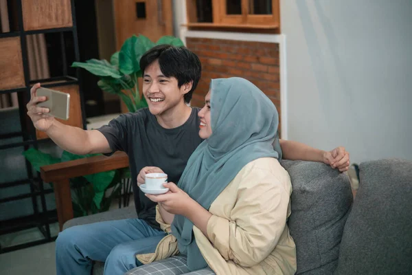 Girl in a hijab and an asian man make video calls using a smart phone — Stock Photo, Image