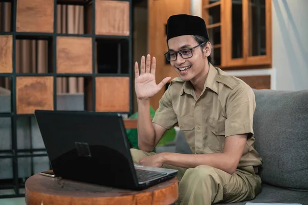 Homem de uniforme civil usar laptop enquanto sentado com gestos de mão para dizer olá — Fotografia de Stock