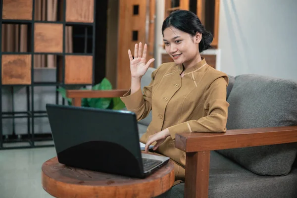 Mulher em uniforme civil usar laptop enquanto sentado com gestos de mão para dizer olá — Fotografia de Stock
