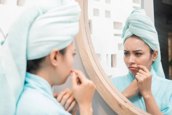 Menina tristeza com espinha na bochecha quando olha para o espelho — Fotografia de Stock