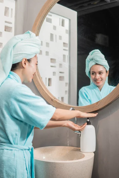 Азиатка улыбается мыть руки с мылом в раковине — стоковое фото