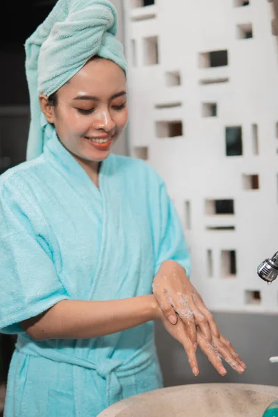 Menina asiática usa uma toalha de banho enquanto lava a parte de trás de sua mão com sabão para torcer — Fotografia de Stock