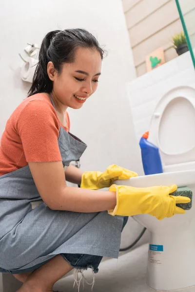Asijské ženy nosí rukavice čistit záchod s houbou — Stock fotografie