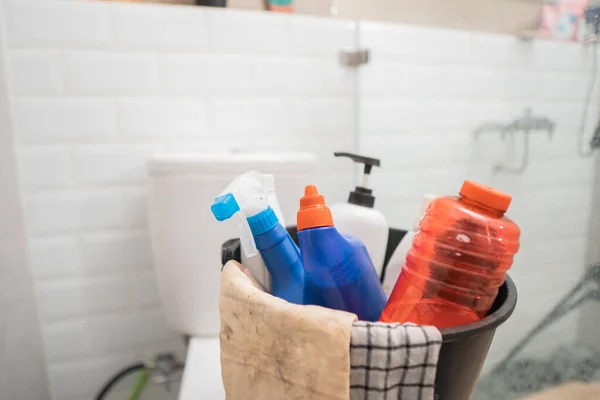 Pulverizador de botellas, botella de líquido de limpieza y trapo en un cubo en el baño — Foto de Stock