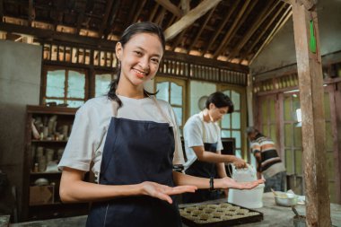 Önlüklü güzel bir çalışan sana avuçlarından bir şey sunuyor.