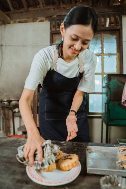 Pastayı önlükle yapan kız yeni pişmiş pastayı masanın üzerine koyar.