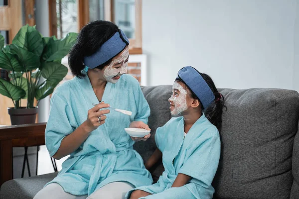 En mamma och hennes lilla flicka leende bär ansiktsmasker titta på varandra medan sitter — Stockfoto