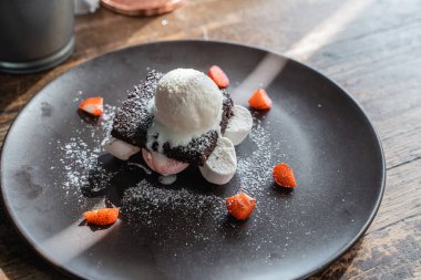 Buzlu şekerli siyah tabakta vanilyalı ve çikolatalı dondurma.