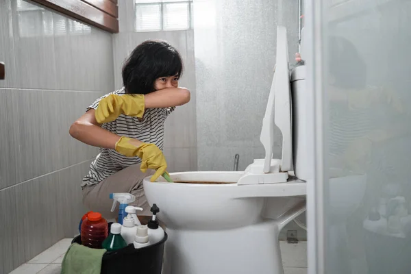 housewife wear gloves over their noses to clean smelly toilet