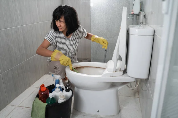 Una mujer molesta usando guantes cepillando el inodoro sucio — Foto de Stock