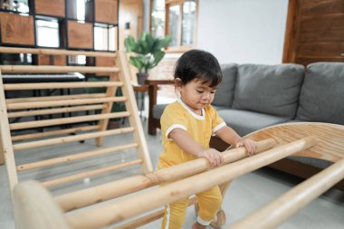 Pikler Üçgeni oyuncaklarına tırmanan bir bebek