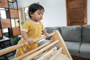 Küçük çocuk aşağı bakar Pikler üçgeni oyuncağına tırmanırken