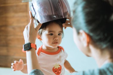 Gitmeden önce annesinin yanında kask takan küçük bir çocuk.