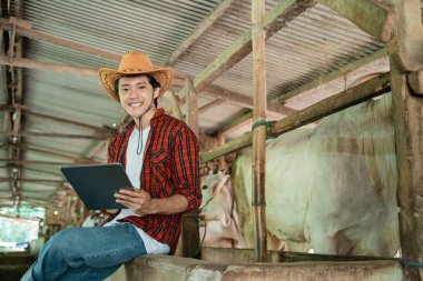 Erkek çiftçi otururken kovboy şapkası takıyor.