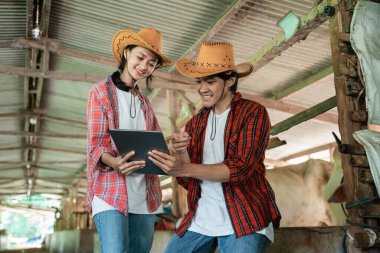 Çiftçi oğlan ve kız birlikte tablete bakıp kullanıyorlar.