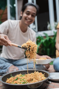 Arkadaşınla piknik yaparken bir kaşık erişte alan bir adam.