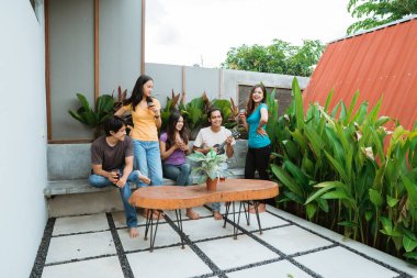 Asyalı arkadaşlar arka bahçede şarkı söyleyip gitar çalarken eğleniyorlar.