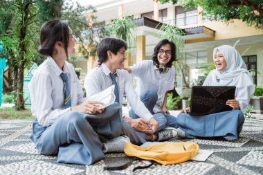 Tartışmalar sırasında dört lise öğrencisine gülümsemek ve gruplar halinde çalışırken dizüstü bilgisayar kullanmak