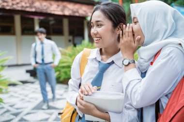 Peçeli bir lise öğrencisi kız arkadaşlarına fısıldıyor: