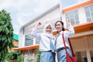 Endonezya 'da lise üniforması ve el kaldıran çanta giyen iki güzel öğrenci.